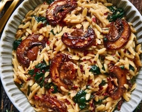 Creamy spinach mushroom chicken orzo served in a bowl with fresh herbs.